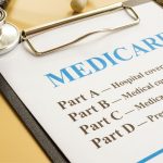 Understanding Medicare Stethoscope on table with medicare form ready to be filled out with all parts listed