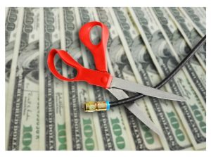Scissors cutting cable cord on top of money 
