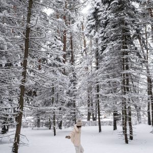 Woman walking through snow-covered trees