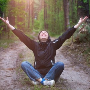 Woman happily meditates on nature path