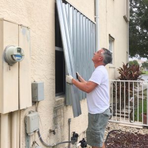 Man putting up hurricane window protection