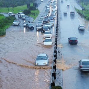 Cars trying to drive through flooded roadway