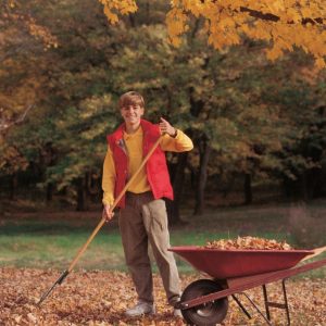 Teen boy raking leaves cheerfully