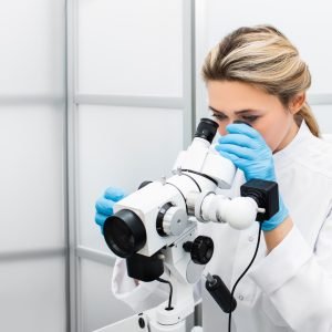 woman looking through microscope