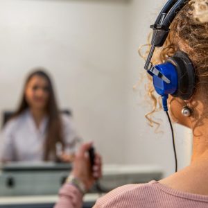 Woman wearing headphones and holding a clicker for a hearing test