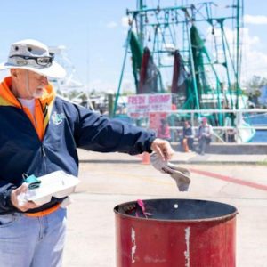Man in sailing gear placing a pair of sock into burning barrel