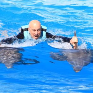 Man holding onto dolphin fins as they pull him through the water