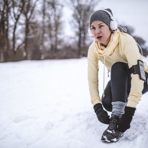 Woman tying her shoe, exercising outdoors in the show