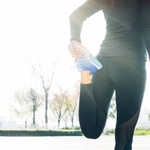 Woman wearing exercise clothing stretches her quad
