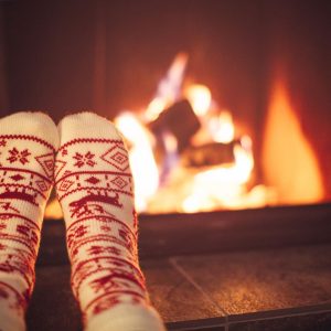 Feet wearing cozy socks in front of a fire