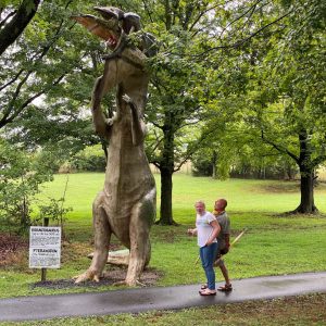 Two people looking at a dinosaur sculpture