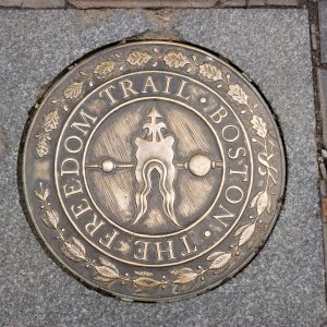 circular brass plaque inset on cement, depicting the logo of the Boston Freedom Trail