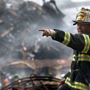 A fireman yells out directions while pointing at something, standing in front of smoking rubble from World Trade Center on Sept. 11, 2001