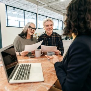 A couple reviews documents happily, while talking to someone in front of a laptop