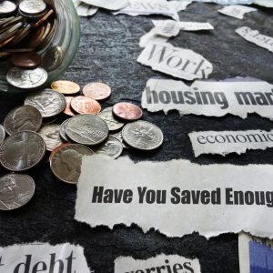 loose coins and phrases written on scrap paper like "have you saved enough" are scattered across a surface 