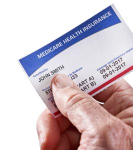 man's hand holds a Medicare card with a white background