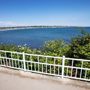 view from a pedestrian walk with white wrought-iron handrails looking over the ocean