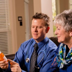 a doctor sits next to his patient (an older woman) while he explains something about a prescription medication