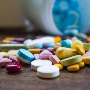 Image of prescription drugs scattered across a tabletop, seemingly spilling out of a bottle