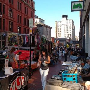 Scene from a busy city street, with vendors lining the sidewalks