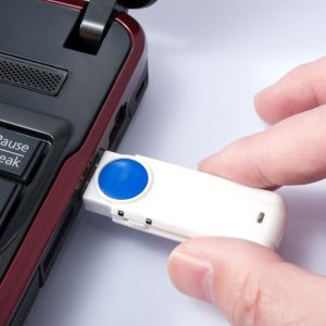 Someone is holding a flash drive while it's inserted into a laptop's USB port