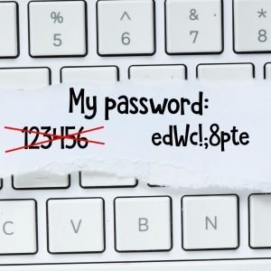 A handwritten note sits atop a white computer keyboard that reads "My password: [the numbers 123456 crossed out] and then "edWc!;8pte"