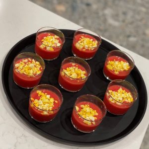 Black tray with glasses containing a fuschia drink and a yellow garnish