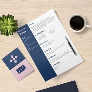 Overhead view of a beautifully-designed resume with navy color-blocking sitting on a desk with a cup of coffee and a succulent plant.