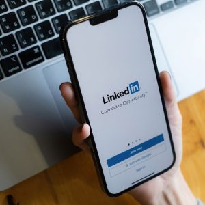 A hand is holding a phone with the screen for "linkedIn" on it