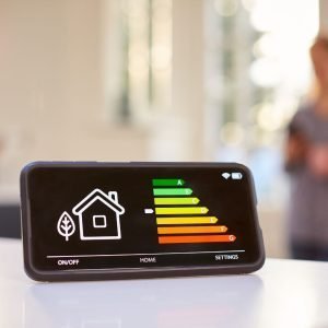 A cellphone displays a screen with a house icon and indicators to display the thermostat's setting
