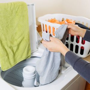 a woman's hands are pulling clothes out of the washer to put in the dryer