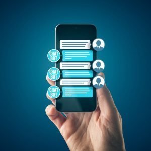 A hand is holding up a cell phone with a screen that has a chat depicted on it. The sender is a human icon, and the person they're chatting with is labeled "chatbot"