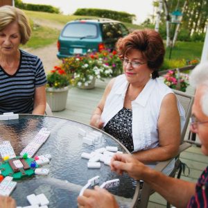 group of people playing mahjong at an outdoor patio table in the summer time