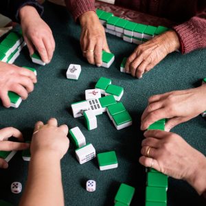 Overhead image of card table with people playing mahjong