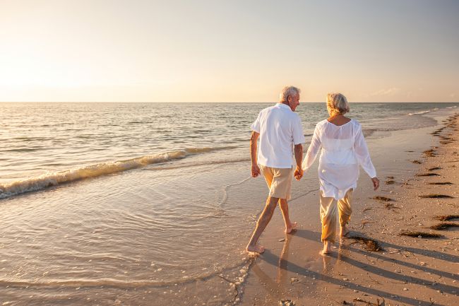 Senior couple walks along beach
