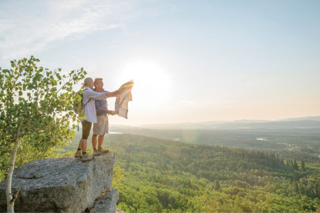 Couple atop rock summit, holding map