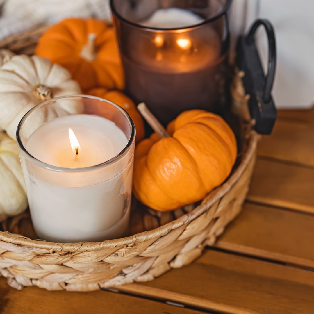 one way to make your home cozy for fall - a basket sitting on a countertop, filled with tiny pumpkin gourds and lit candles