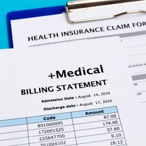 a close-up of the top right corner of a medical billing statement, sitting on top of a clipboard with a health insurance claim form