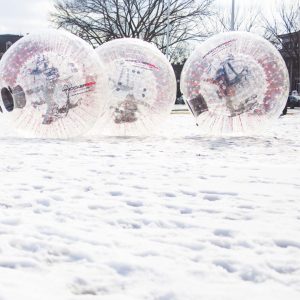 People rolling in zorb balls across snow at Dartmouth Winter Carnival.