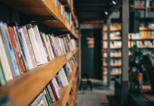 Celebrating the Magic of Libraries and Bookstores in Fiction rows of books in a bookstore_featured image for On our Nightstand feature