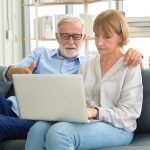 Got Medicare? Big Changes Are Coming in 2026 Couple discussing something while looking at a laptop.