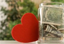 Charitable Giving: The Differences Between Types of Financial Donations Red Heart and Donation Jar with Money on Table against Blurred Background_ Featured image for Charitable Giving article