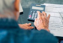 What Longevity Calculators Can — and Can’t — Tell You senior adult uses calculator sitting next to retirement paperwork