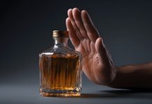 The Health Benefits of (Even Temporary) Alcohol Abstinence Hand refusing bottle of amber looking alcohol_featured image for sober october courtesy of Axel Makhalov
